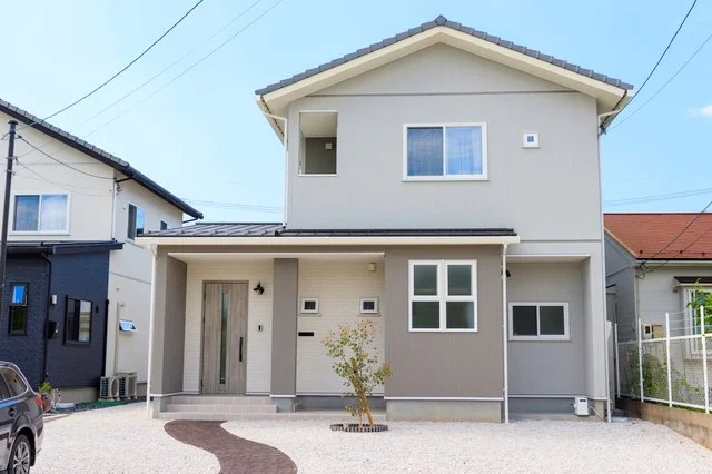 洗い出しのアプローチと木調門柱を備えた戸建て住宅の門まわり全景